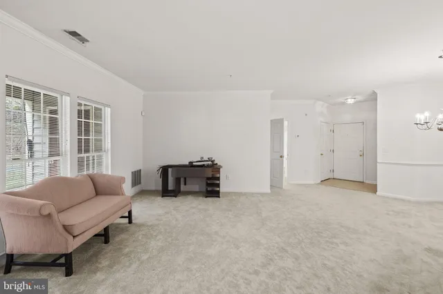 an empty room with chandelier fan and windows