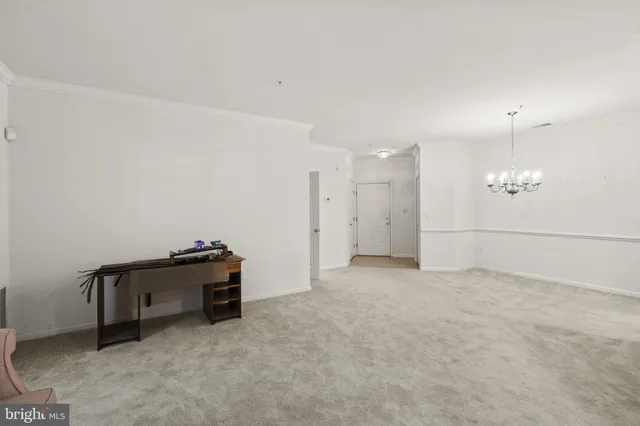 a view of an empty room with kitchen and a window