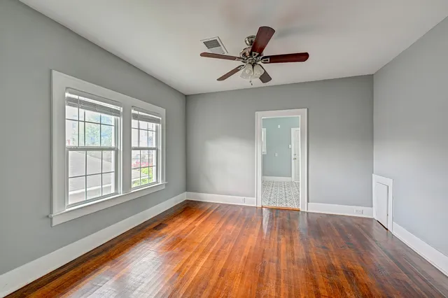 a view of empty room with wooden floor and fan
