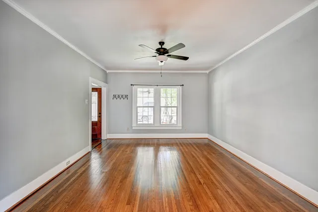 a view of empty room with wooden floor and fan
