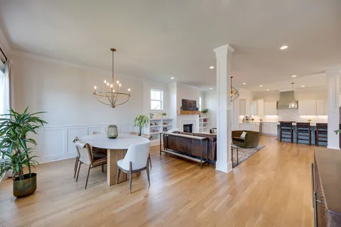 a view of a dining room and livingroom with furniture wooden floor a chandelier