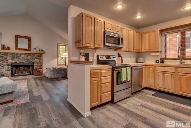 a kitchen with stainless steel appliances granite countertop a stove top oven a sink dishwasher and a refrigerator with wooden floor