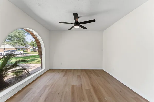 a view of empty room with wooden floor and fan
