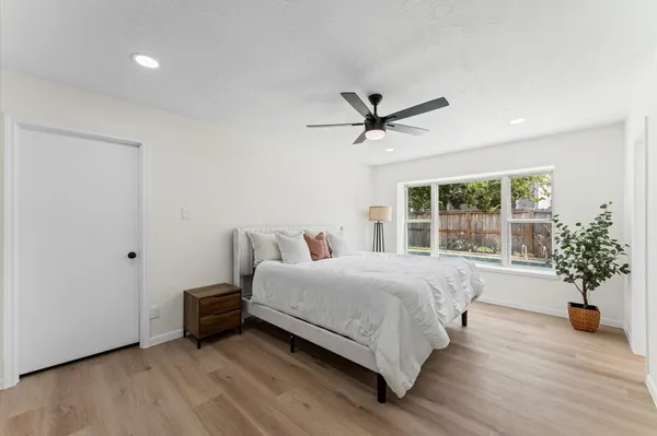 a spacious bedroom with a bed a chandelier and a large window