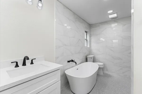 a bathroom with a white tub sink and mirror