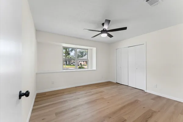 a view of empty room with wooden floor and fan