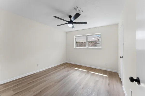 an empty room with wooden floor a ceiling fan and windows