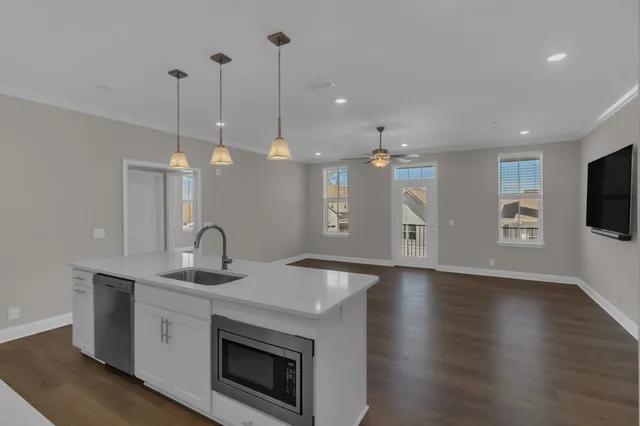 a kitchen with stainless steel appliances granite countertop a sink a microwave a stove and a wooden floor