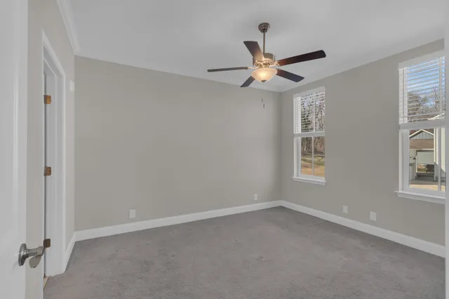 an empty room with windows and fan