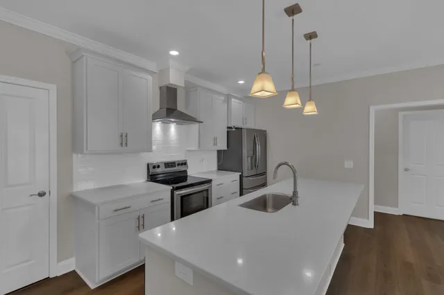 a kitchen with stainless steel appliances granite countertop a sink a stove a refrigerator and island with wooden floor