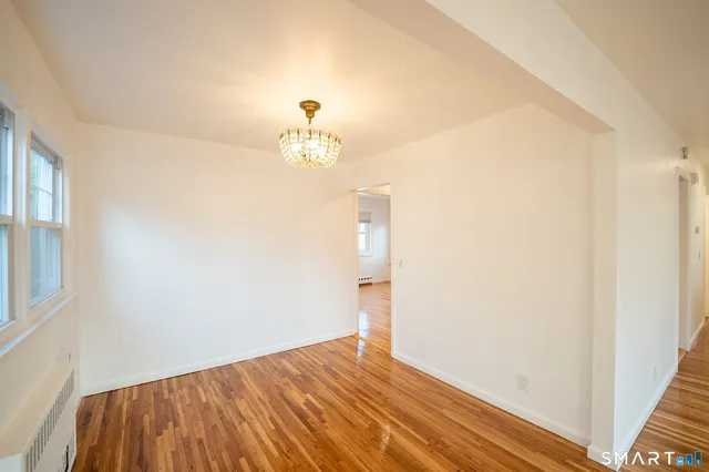 a view of empty room with wooden floor and window