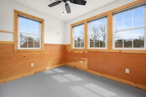 a view of an empty room with a window and a ceiling fan