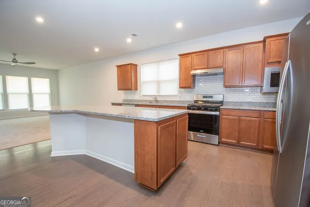 a kitchen with stainless steel appliances granite countertop a sink and a refrigerator