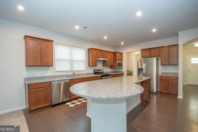 a large kitchen with granite countertop a sink and white cabinets