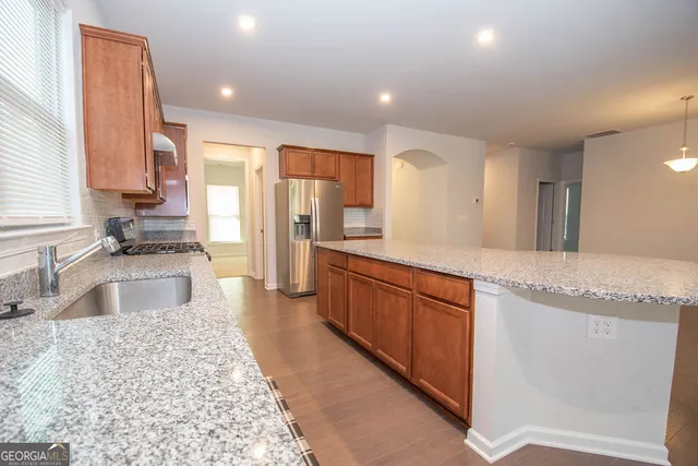 a large kitchen with stainless steel appliances granite countertop a lot of counter space and a sink