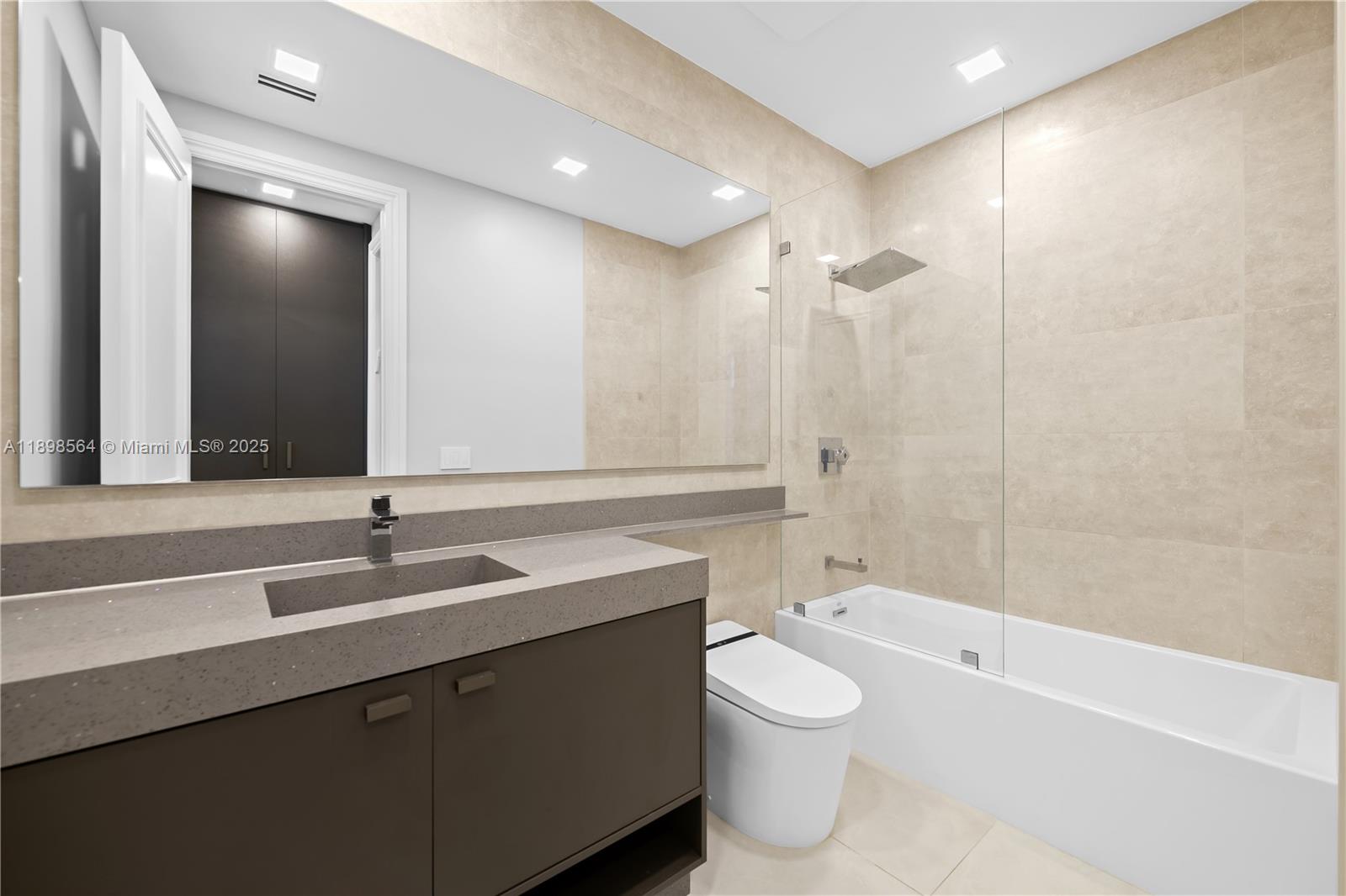 1530 Island Boulevard Aventura, FL 33160 - Photo 49 of 99 a bathroom with a granite countertop sink a toilet a mirror and bathtub