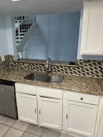 a kitchen with granite countertop white cabinets and sink