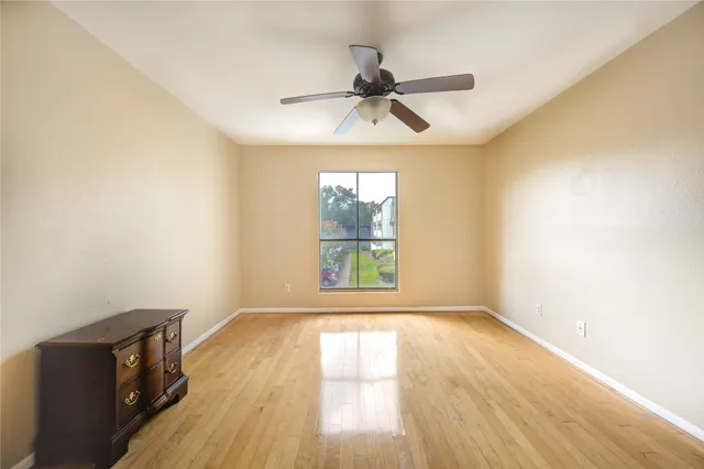 an empty room with wooden floor fan and windows