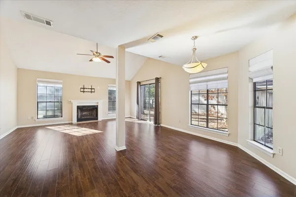 a view of an empty room with wooden floor fireplace and a window