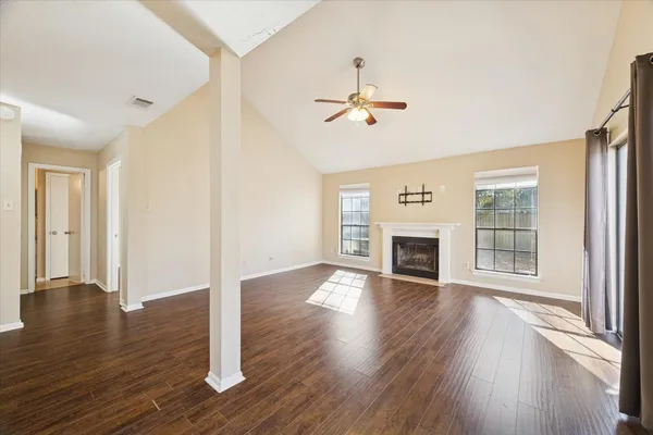 a view of an empty room with wooden floor fireplace and a window