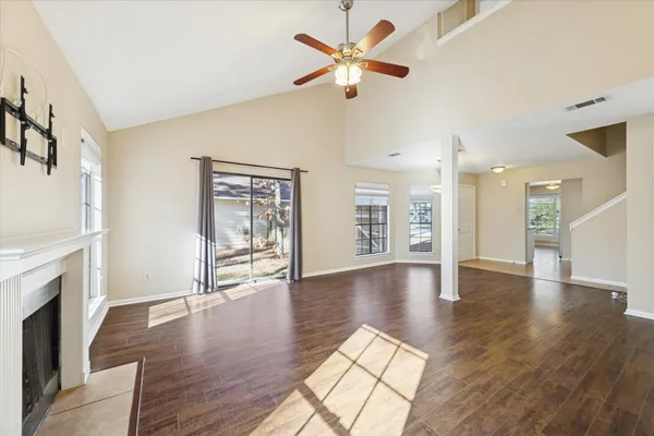 a view of an empty room with wooden floor and a fireplace