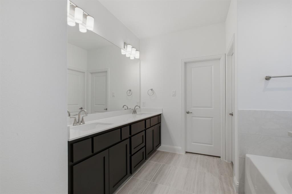 2911 Hanscom Street Forney, TX 75126 - Photo 6 of 40 Bathroom featuring a double vanity with dark wood-finish cabinetry, white countertops, and brushed nickel faucets