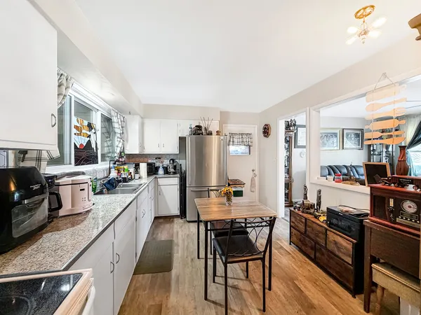 a kitchen with stainless steel appliances kitchen island granite countertop a stove top oven a sink dishwasher a dining table and chairs with wooden floor