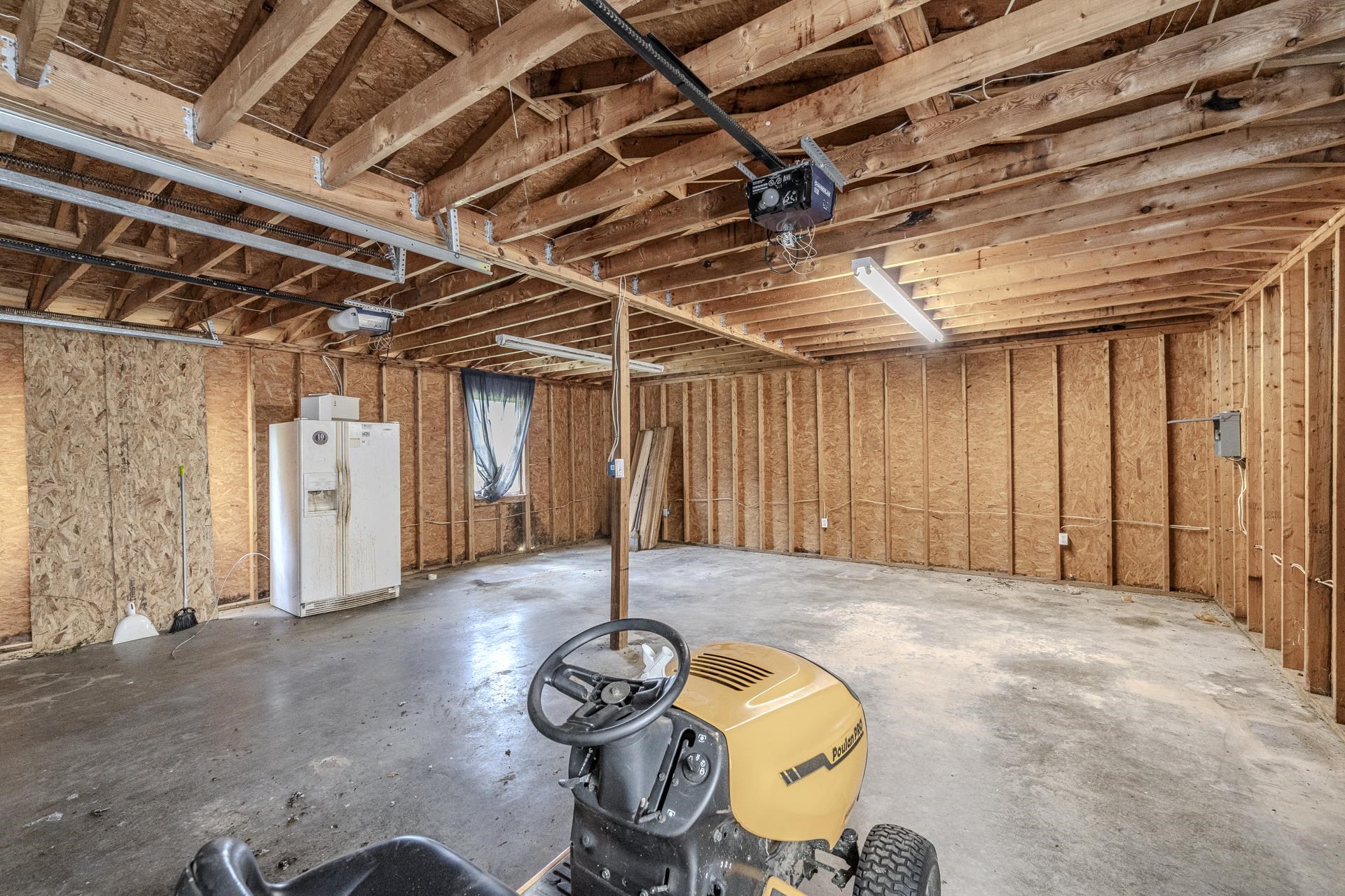 859 Old Morris Chapel Road Adamsville, TN 38310 - Photo 13 of 39 Spacious garage featuring exposed wood beam ceiling, concrete flooring, and ample wall framing