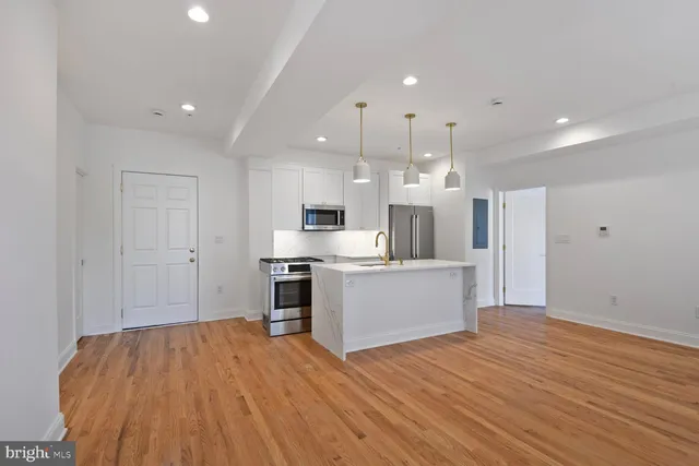a large kitchen with a wooden floor and stainless steel appliances