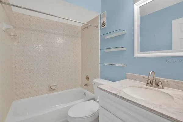 a bathroom with a granite countertop bathtub shower sink vanity mirror and toilet