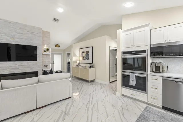 a living room with stainless steel appliances furniture a flat screen tv and a fireplace