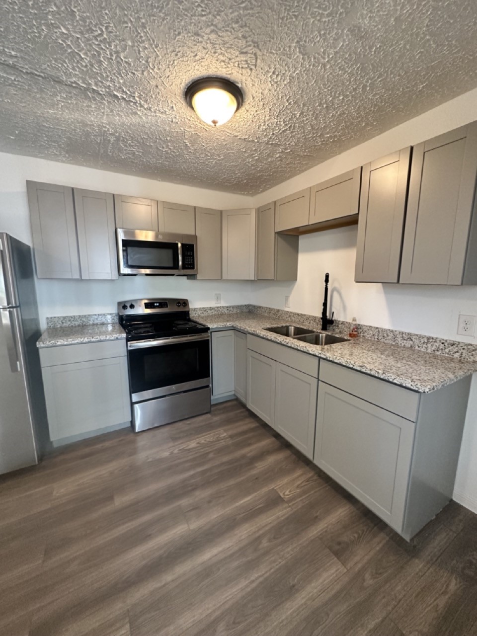 978 Ringold Street, Unit B Houston, TX 77088 - Photo 7 of 12 a kitchen with stainless steel appliances granite countertop a sink a stove top oven and wooden floors