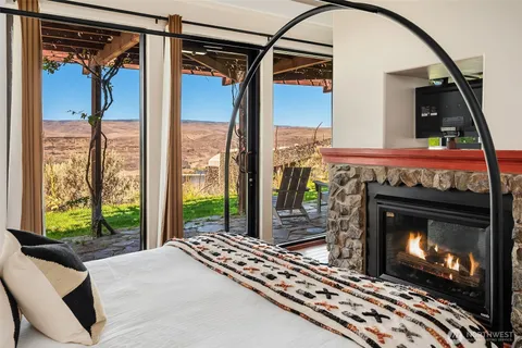 a living room with a fireplace a flat screen tv and a floor to ceiling window