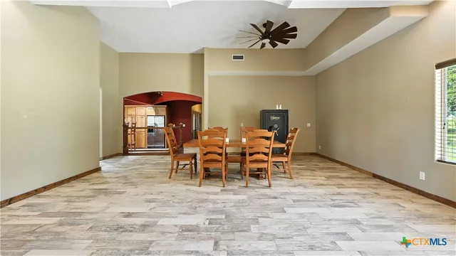 a dining hall with stainless steel appliances kitchen island granite countertop a table chairs and a refrigerator