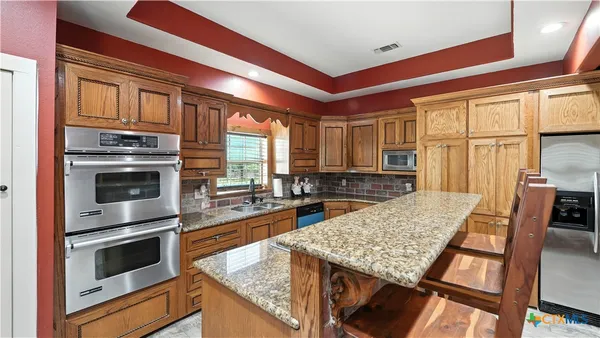 a kitchen with stainless steel appliances granite countertop a stove a sink and a wooden cabinets