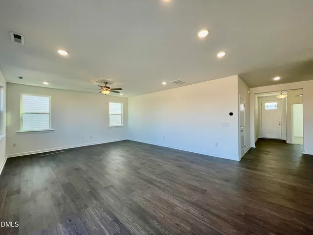 an empty room with wooden floor and natural light
