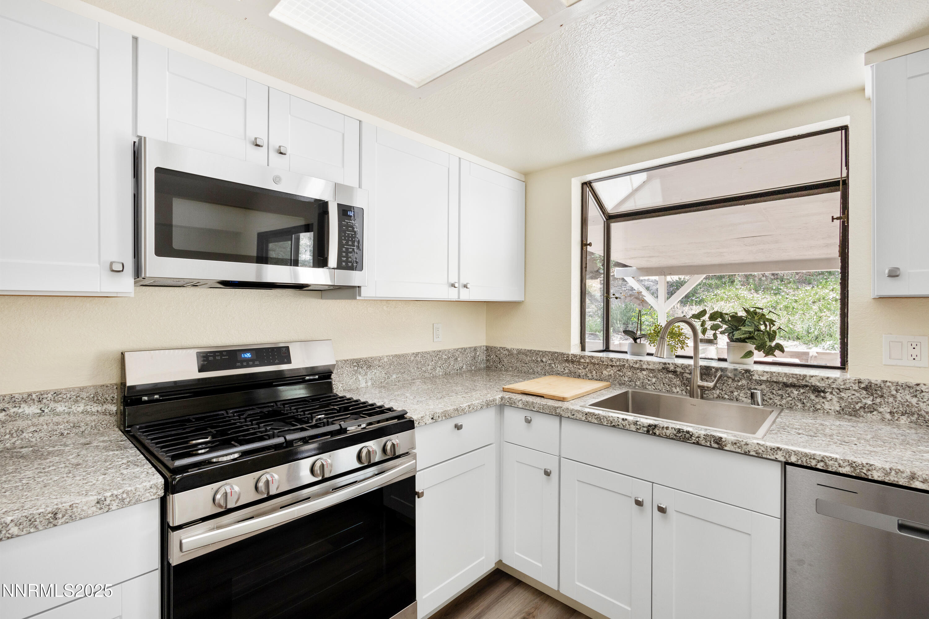 5809 Sydney Court Reno, NV 89523 - Photo 10 of 28 a kitchen with granite countertop a stove a sink and a microwave