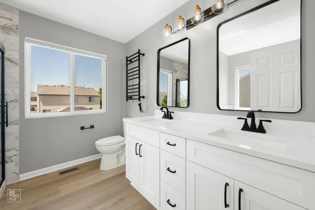 a bathroom with a toilet a sink a mirror and a window