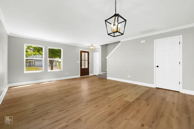 an empty room with wooden floor cabinet and windows