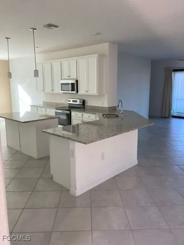 a large kitchen with granite countertop a sink and a stove top oven