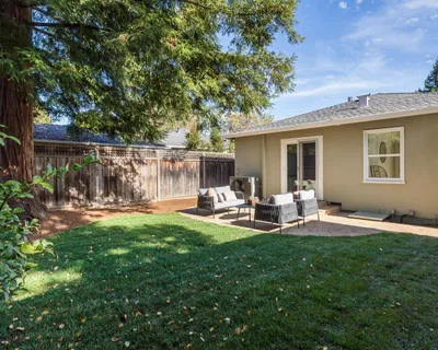 a view of backyard of house with outdoor seating and green space