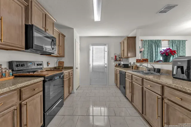 a large kitchen with stainless steel appliances granite countertop a stove and cabinets