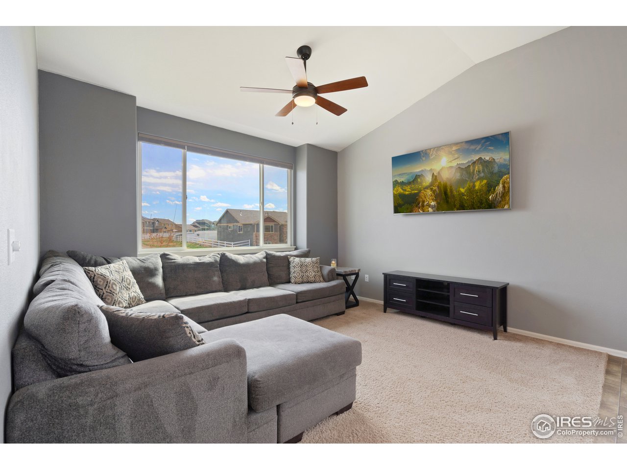 8705 13th St Road Greeley, CO 80634 - Photo 2 of 40 The living room has a big picture window, vaulted ceiling, carpeted floors and is open to the dining area and kitchen.