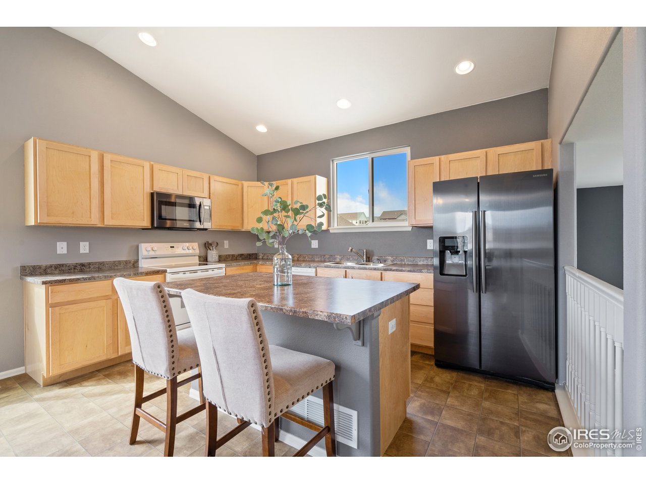 8705 13th St Road Greeley, CO 80634 - Photo 3 of 40 The kitchen has oak cabinets, laminate floors and counters, electric appliances, an island counter and breakfast bar seating.