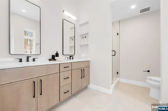 a spacious bathroom with 2 sink toilet and shower