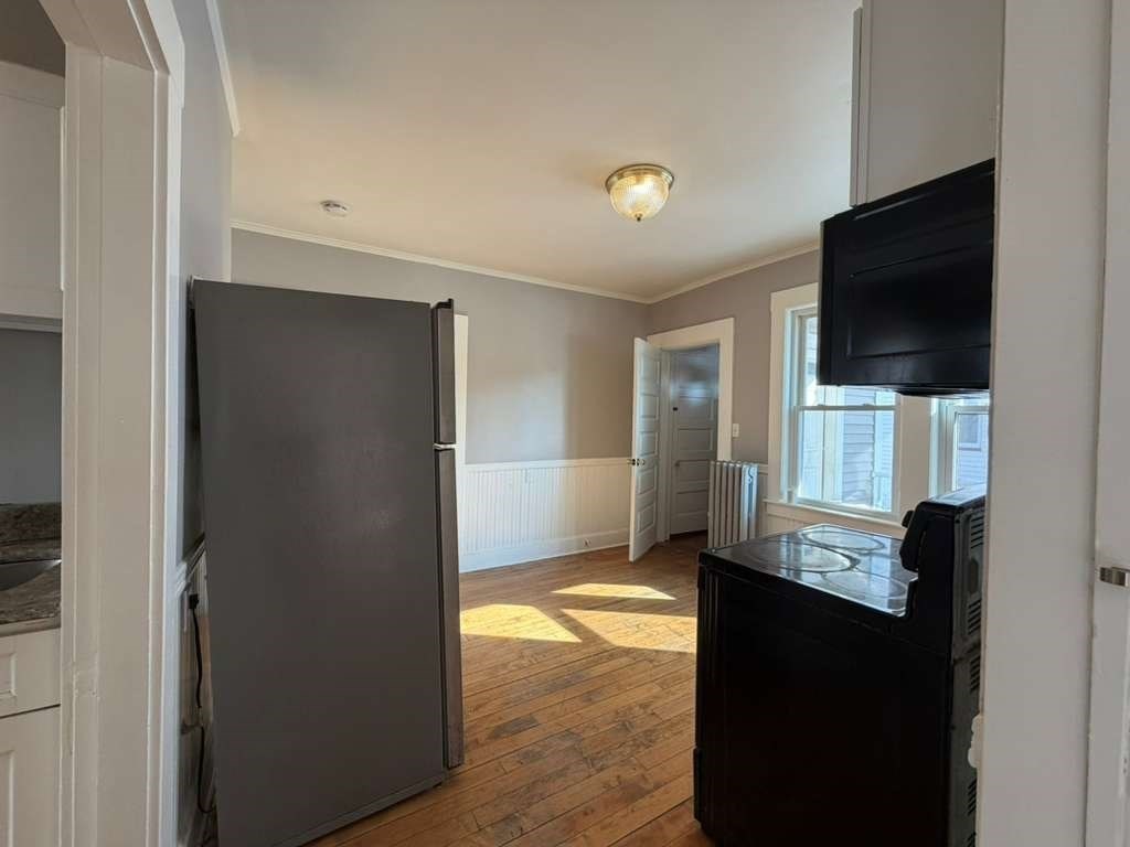 246 Rogers Street, Unit 1 Lowell, MA 01852 - Photo 12 of 17 a view of a livingroom with wooden floor and a flat screen tv