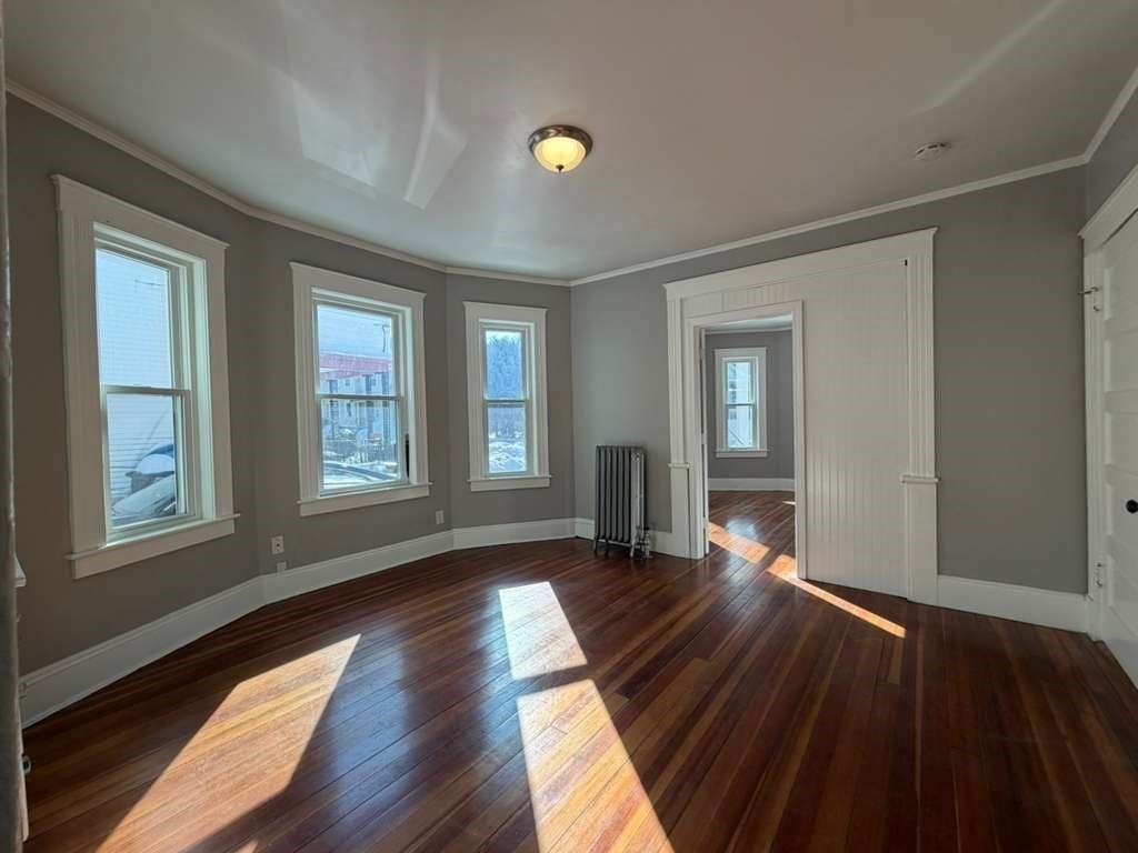 246 Rogers Street, Unit 1 Lowell, MA 01852 - Photo 7 of 17 wooden floor in an empty room with a window