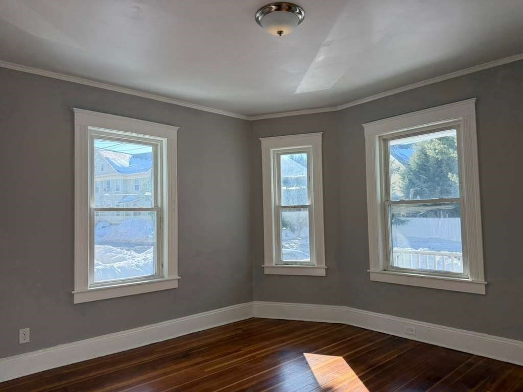 246 Rogers Street, Unit 1 Lowell, MA 01852 - Photo 8 of 17 a view of an empty room with wooden floor and a window