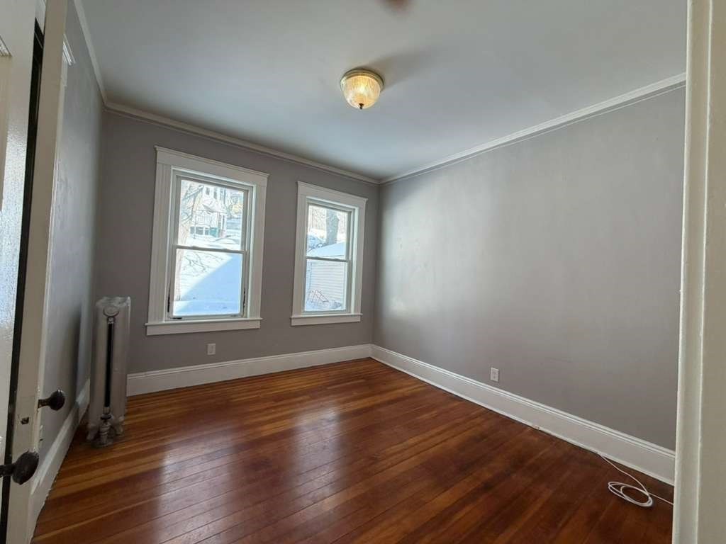 246 Rogers Street, Unit 1 Lowell, MA 01852 - Photo 9 of 17 an empty room with wooden floor and windows