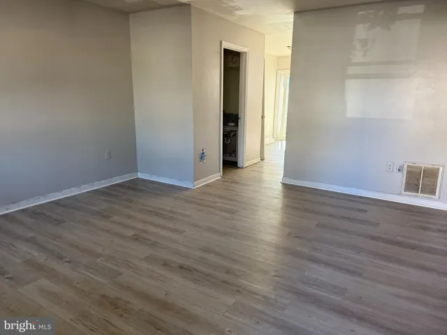 a view of an empty room with wooden floor and closet